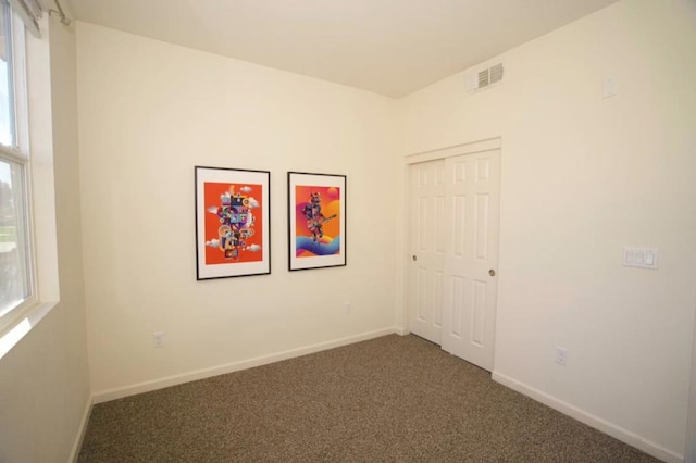 unfurnished room with dark colored carpet