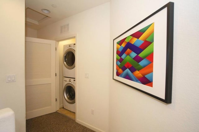 washroom with stacked washing maching and dryer and dark carpet