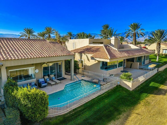 rear view of house with a fenced in pool, a lawn, and a patio