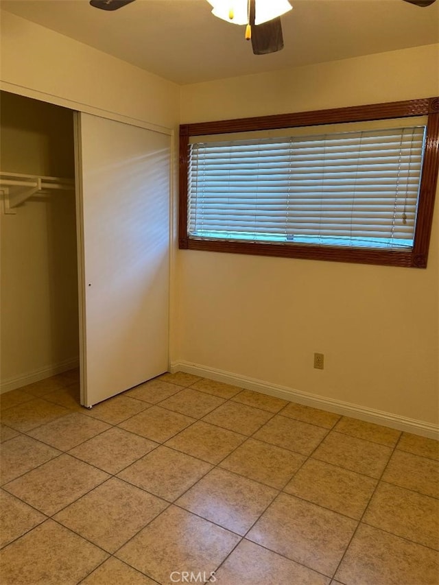 unfurnished bedroom with a closet, baseboards, a ceiling fan, and light tile patterned floors