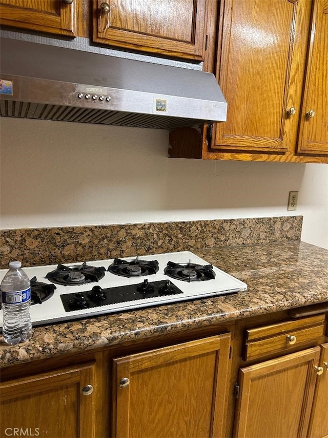 details with white gas cooktop, brown cabinetry, and under cabinet range hood