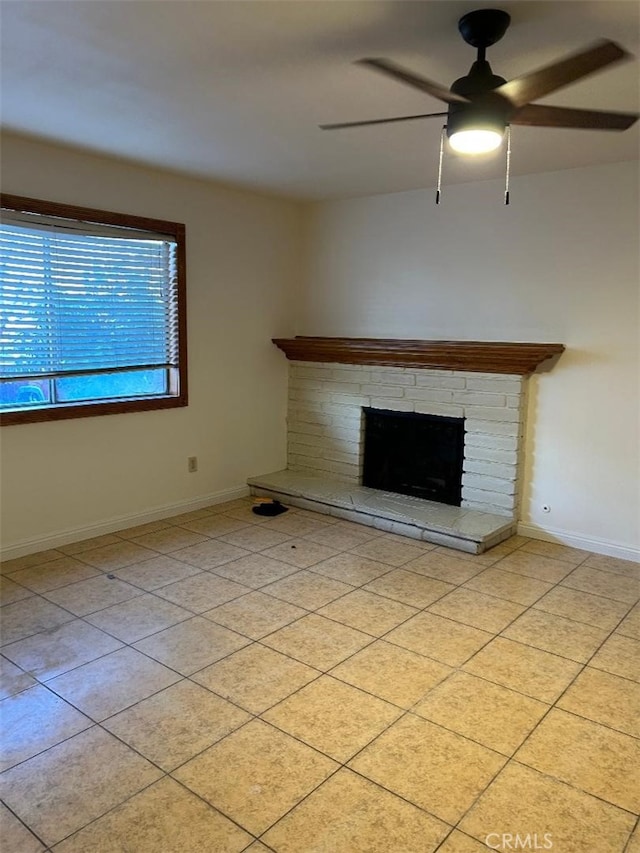 unfurnished living room with light tile patterned floors, a brick fireplace, a ceiling fan, and baseboards