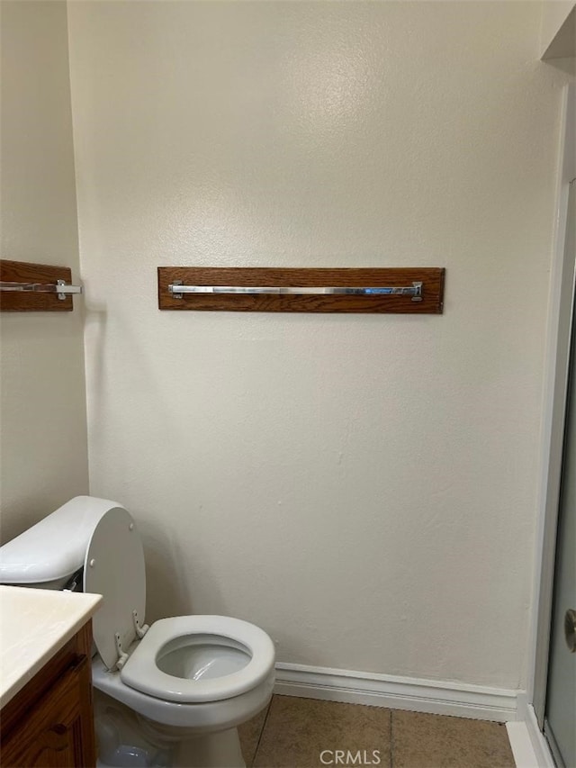 bathroom with baseboards, toilet, vanity, and tile patterned flooring