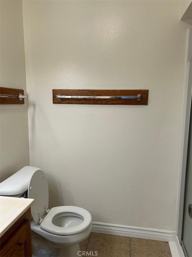 bathroom featuring toilet, vanity, baseboards, and tile patterned flooring