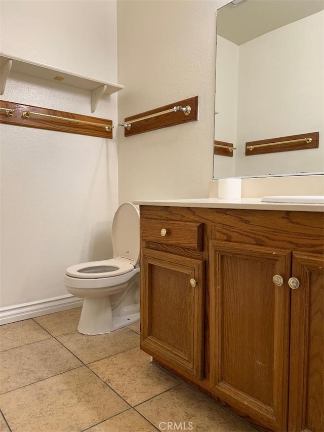 half bathroom with tile patterned floors, toilet, vanity, and baseboards
