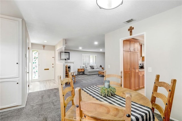 dining space featuring light carpet and a fireplace