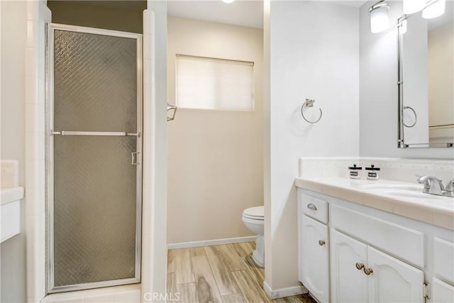 bathroom featuring toilet, vanity, a shower with shower door, and hardwood / wood-style flooring