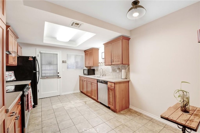 kitchen with appliances with stainless steel finishes, sink, backsplash, light tile patterned floors, and a tray ceiling