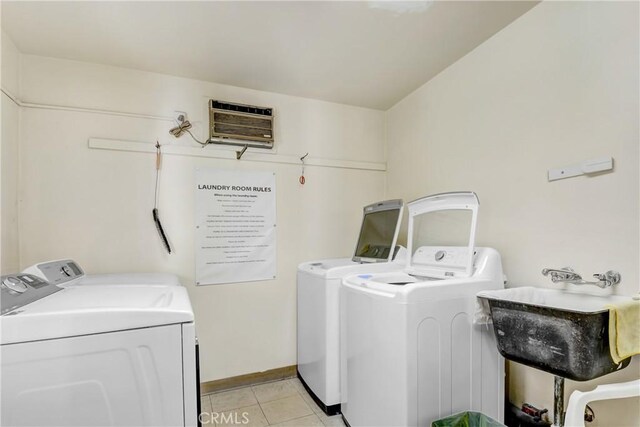 washroom with washer and dryer, sink, light tile patterned floors, and a wall mounted AC