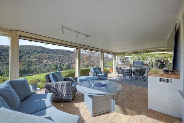 view of patio with a grill, a mountain view, and an outdoor living space with a fire pit