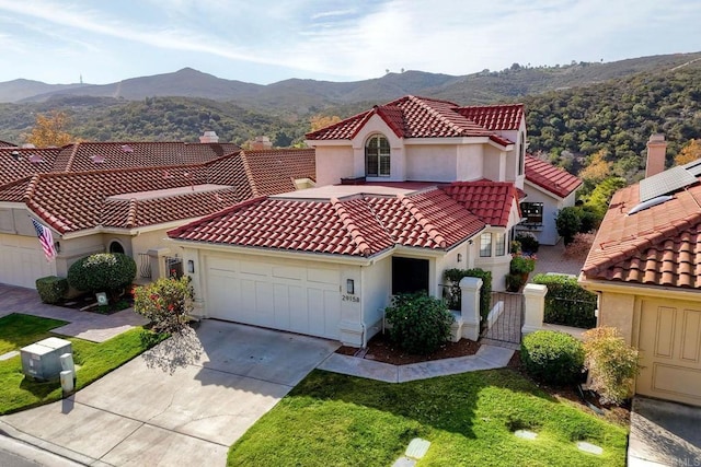 mediterranean / spanish-style house featuring a garage, a mountain view, and a front yard