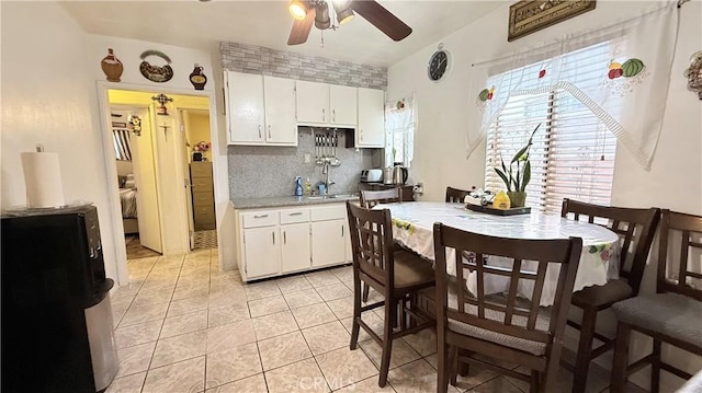 kitchen with tasteful backsplash, white cabinets, light tile patterned flooring, and light countertops