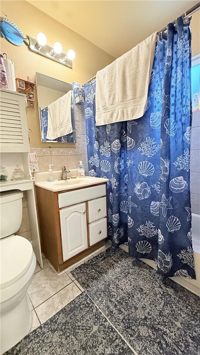 bathroom with tile patterned floors, a shower with curtain, toilet, tile walls, and vanity