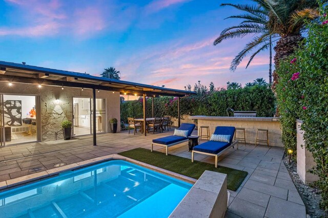 pool at dusk with a patio area