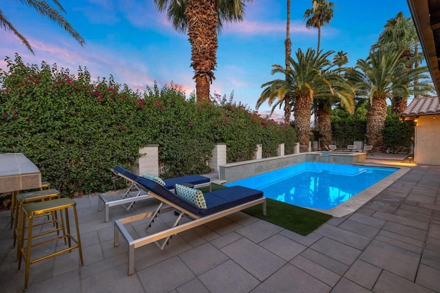 pool at dusk featuring a patio