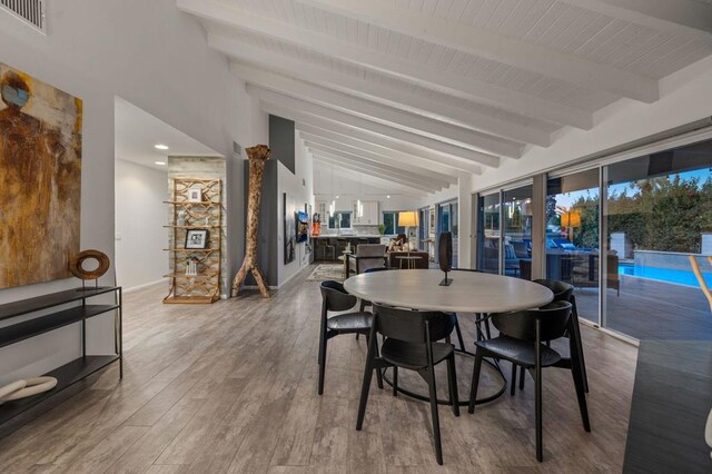 dining room featuring wood-type flooring and vaulted ceiling with beams