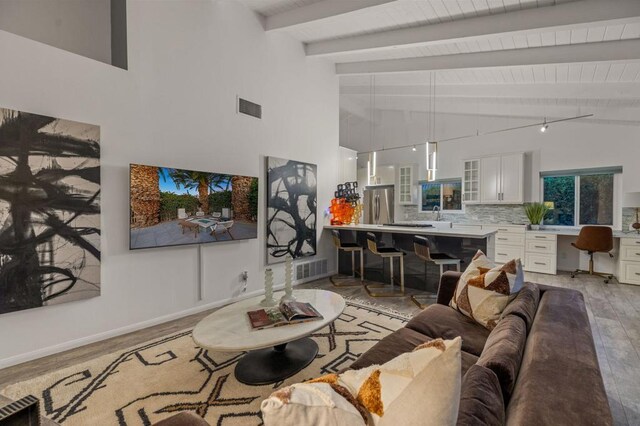 living room with beam ceiling, high vaulted ceiling, and light hardwood / wood-style floors