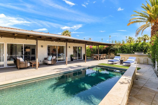 view of swimming pool featuring exterior kitchen and a patio area