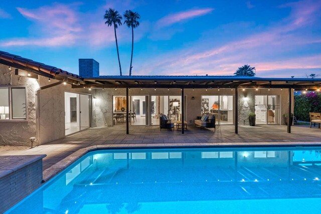 pool at dusk with a patio area