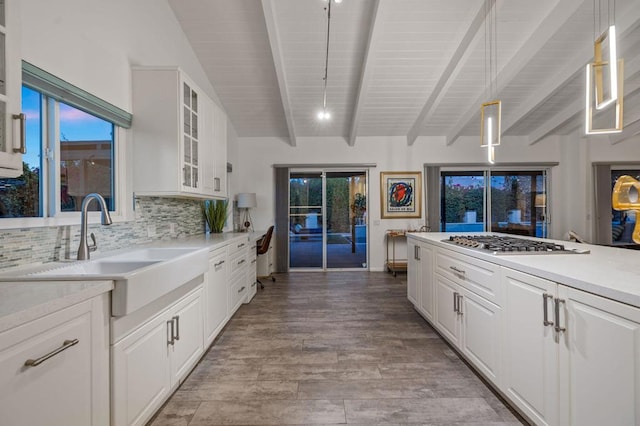 kitchen featuring decorative light fixtures, stainless steel gas stovetop, sink, light hardwood / wood-style flooring, and white cabinets