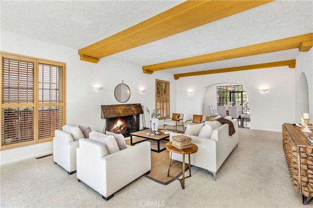 carpeted living room featuring beamed ceiling and a textured ceiling