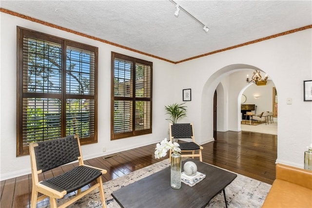 sitting room featuring ornamental molding, dark hardwood / wood-style floors, and a textured ceiling