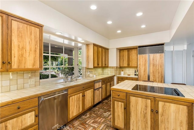 kitchen with tile counters, stainless steel dishwasher, and paneled built in refrigerator