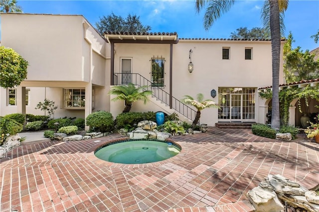 rear view of house featuring a patio and an in ground hot tub