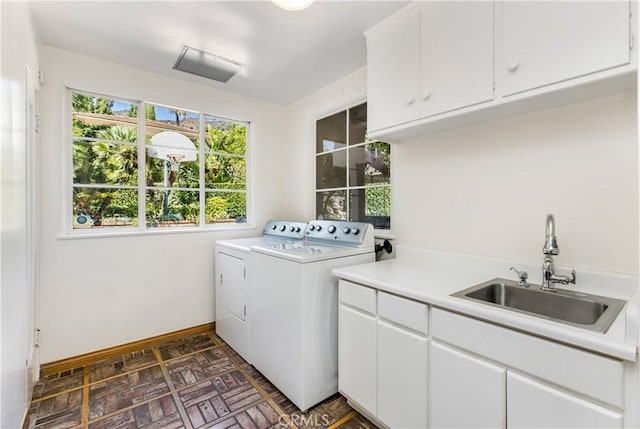 laundry area featuring cabinets, washer and clothes dryer, and sink