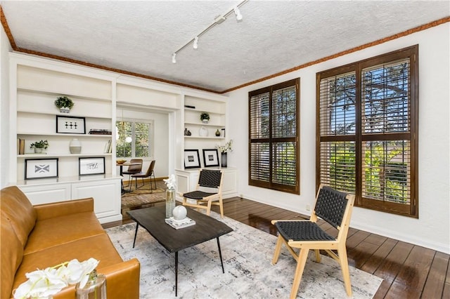 sitting room featuring hardwood / wood-style floors, ornamental molding, and a textured ceiling