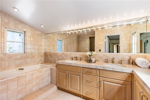 bathroom featuring lofted ceiling, backsplash, vanity, a relaxing tiled tub, and tile patterned floors