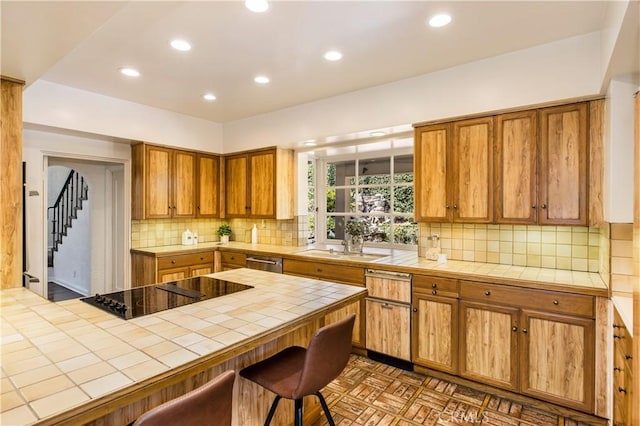 kitchen featuring dark parquet flooring, tile countertops, a kitchen breakfast bar, black electric stovetop, and backsplash