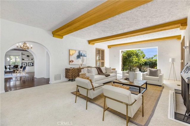 carpeted living room featuring a textured ceiling, a chandelier, and beamed ceiling