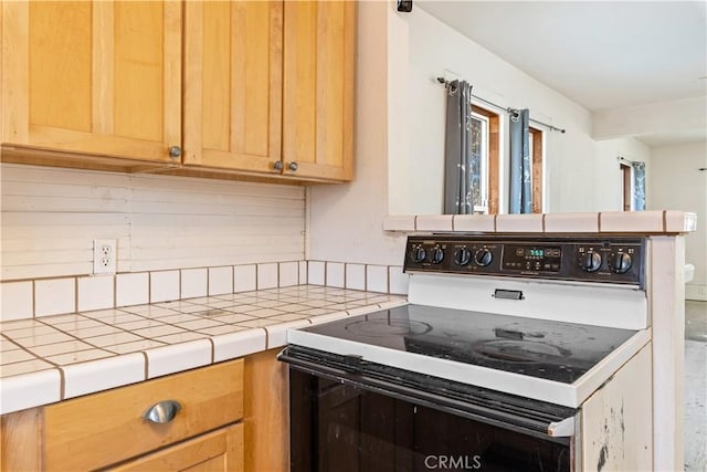 kitchen featuring tile counters, tasteful backsplash, and white range with electric cooktop