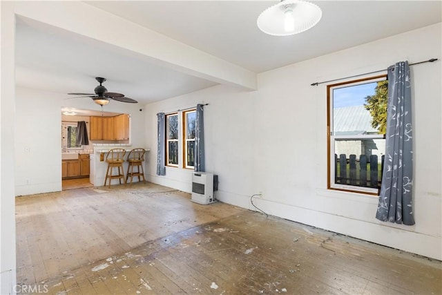 unfurnished living room with ceiling fan, beam ceiling, and light wood-type flooring