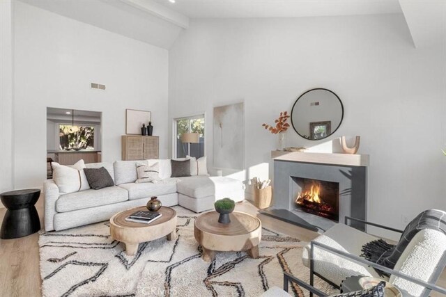 living room featuring hardwood / wood-style flooring, high vaulted ceiling, and beamed ceiling