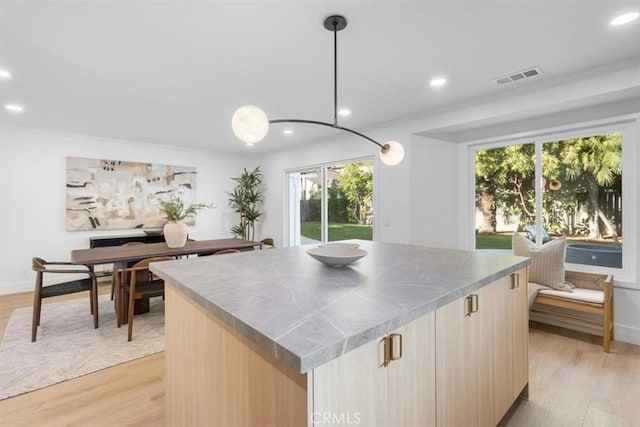 kitchen featuring a kitchen island, light brown cabinets, light hardwood / wood-style floors, and pendant lighting