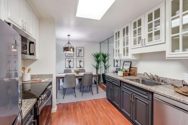 kitchen featuring light stone counters, stainless steel appliances, white cabinetry, and light hardwood / wood-style flooring