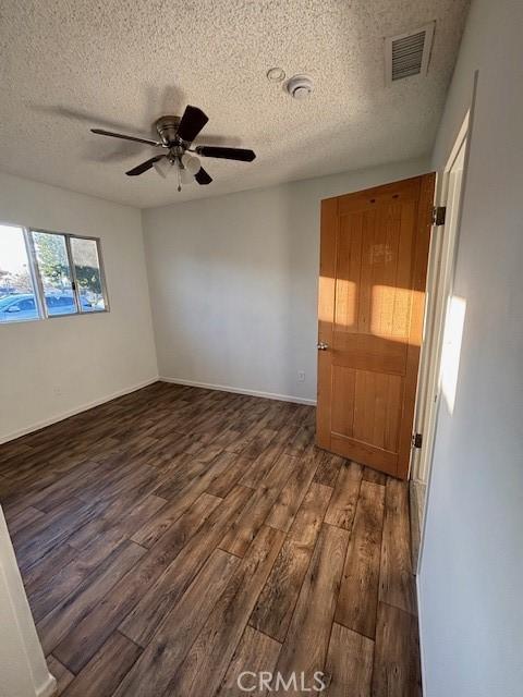 empty room featuring a textured ceiling, ceiling fan, and dark hardwood / wood-style flooring