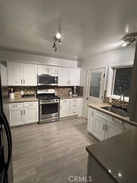 kitchen featuring appliances with stainless steel finishes, sink, white cabinetry, and light hardwood / wood-style flooring