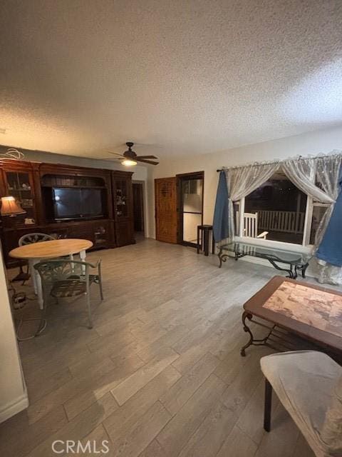 living room with a textured ceiling, ceiling fan, and hardwood / wood-style flooring