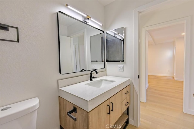 bathroom featuring wood-type flooring, toilet, and vanity