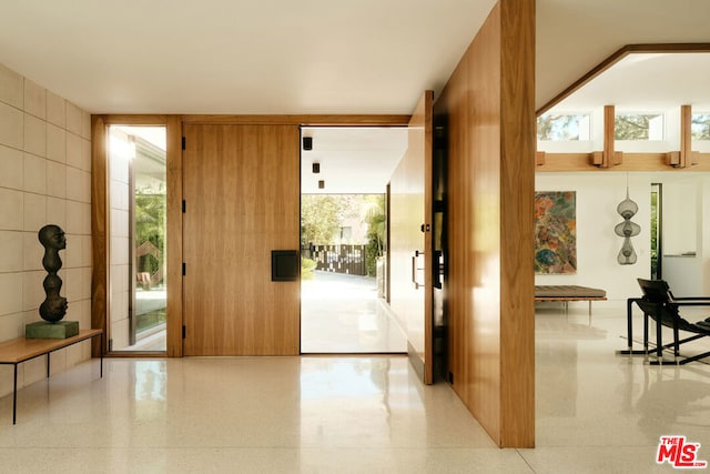 doorway with plenty of natural light, floor to ceiling windows, and wood walls