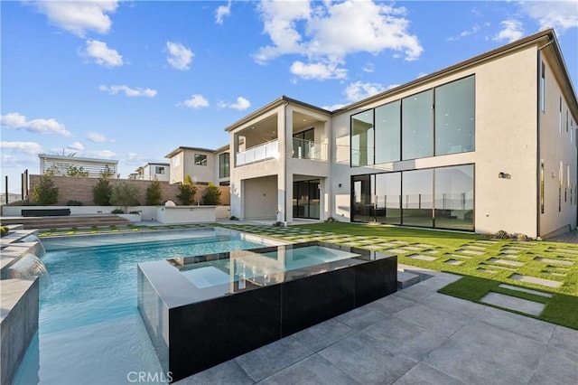 rear view of house with a pool with hot tub, pool water feature, a lawn, and a patio area