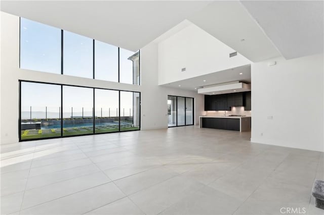 unfurnished living room with light tile patterned floors and a towering ceiling