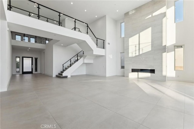 unfurnished living room featuring a large fireplace and a towering ceiling