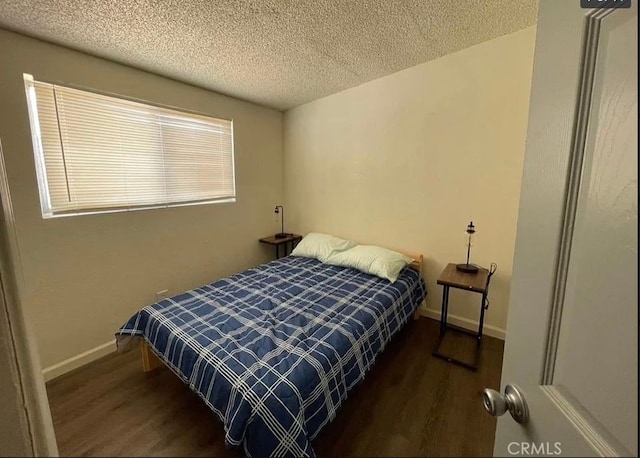 bedroom featuring a textured ceiling and dark hardwood / wood-style floors