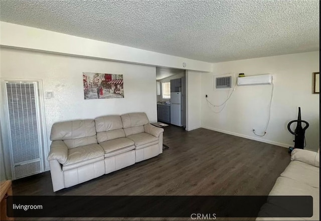 living room featuring dark wood-type flooring, a textured ceiling, and a wall mounted air conditioner