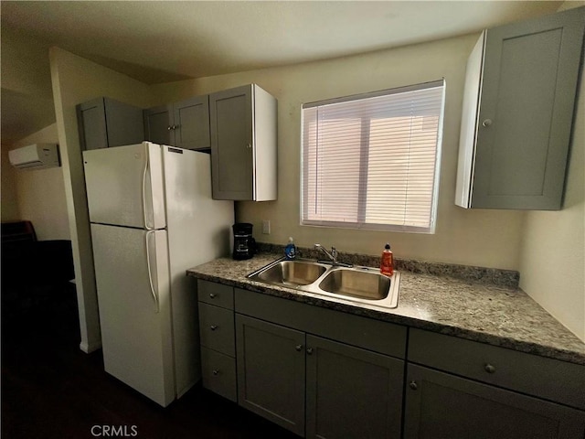 kitchen with white fridge, gray cabinetry, a wall mounted AC, and sink