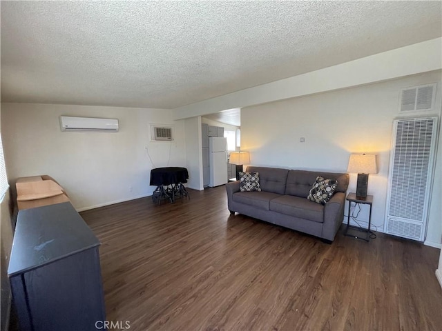 living room featuring a wall mounted AC, dark hardwood / wood-style floors, and a textured ceiling